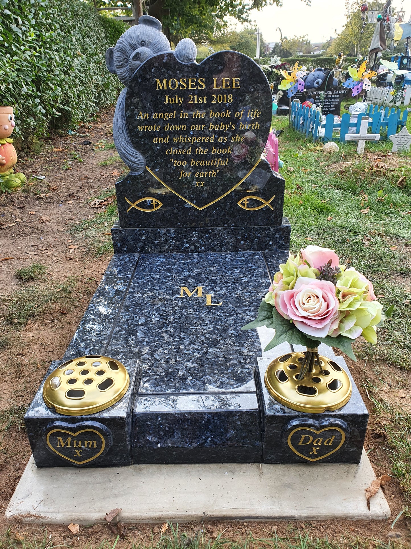 Carved teddy bear holding heart memorial with vase to rear