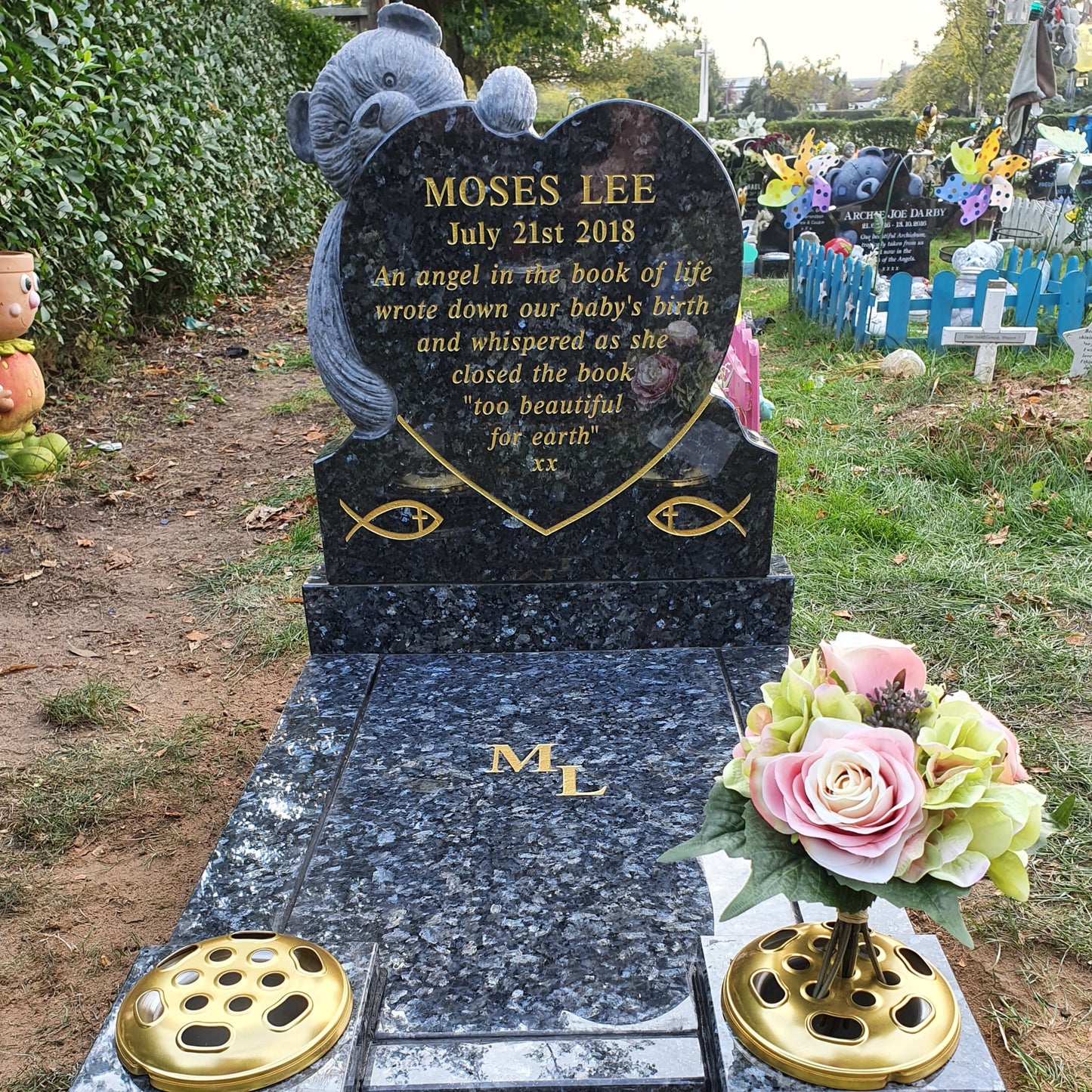 Carved teddy bear on a round top memorial with square base