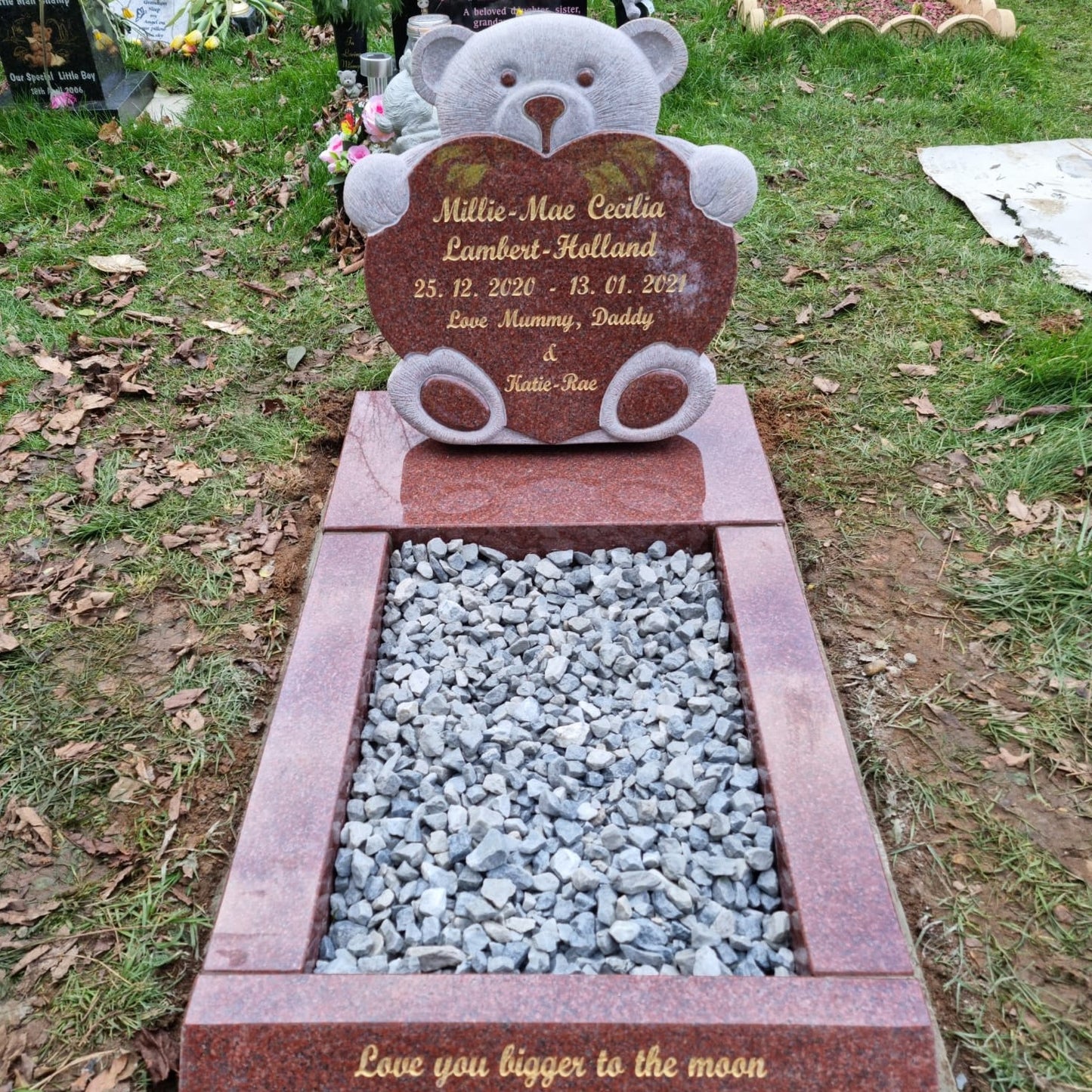 Carved teddy bear on a round top memorial with square base