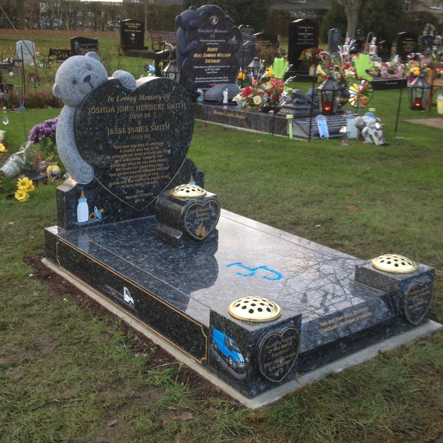 Carved teddy bear on a round top memorial with square base